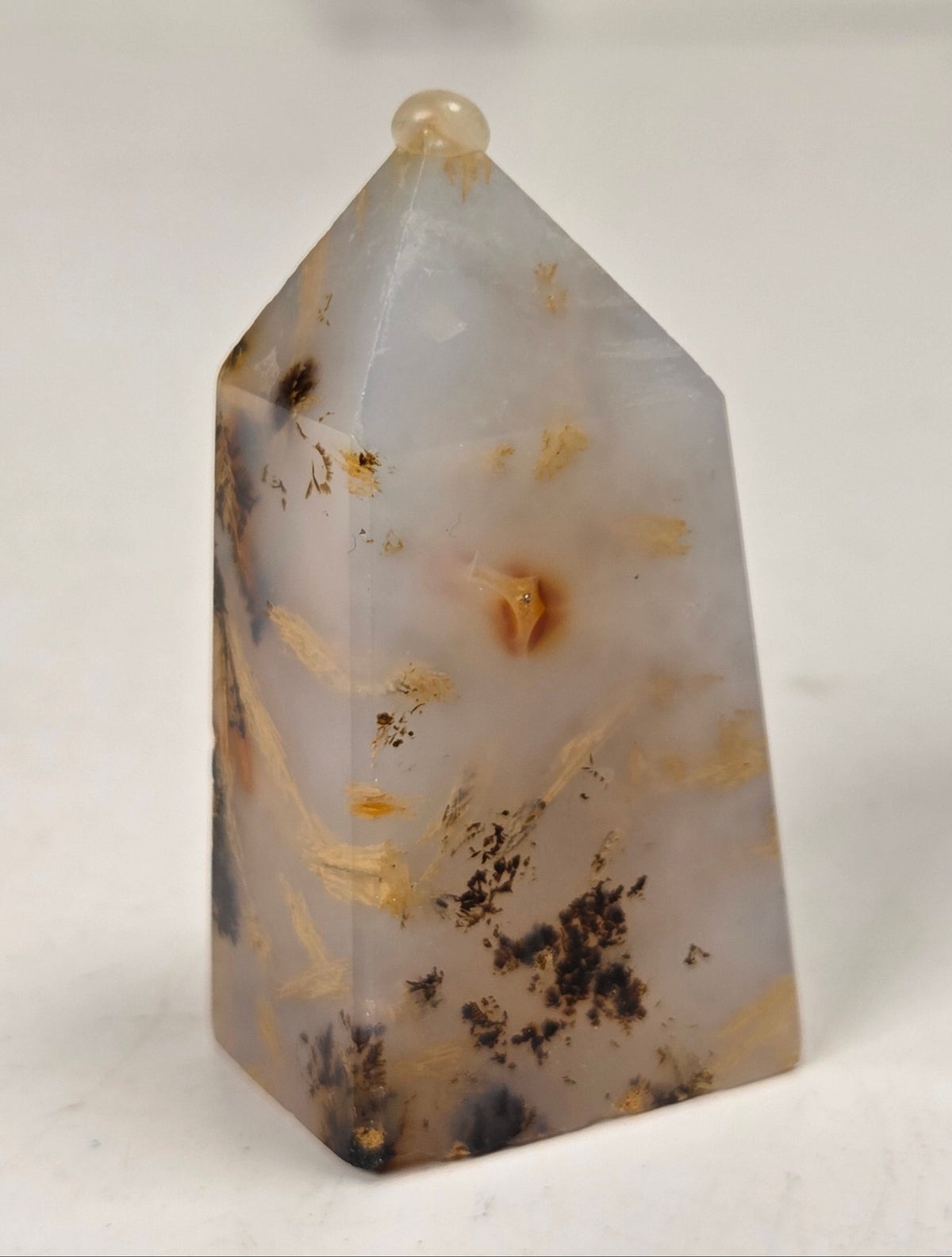 Close-up of a crystal point with inclusions against a white background
