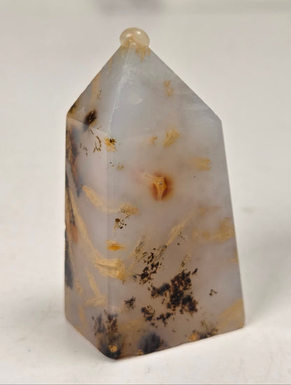 Close-up of a crystal point with inclusions against a white background