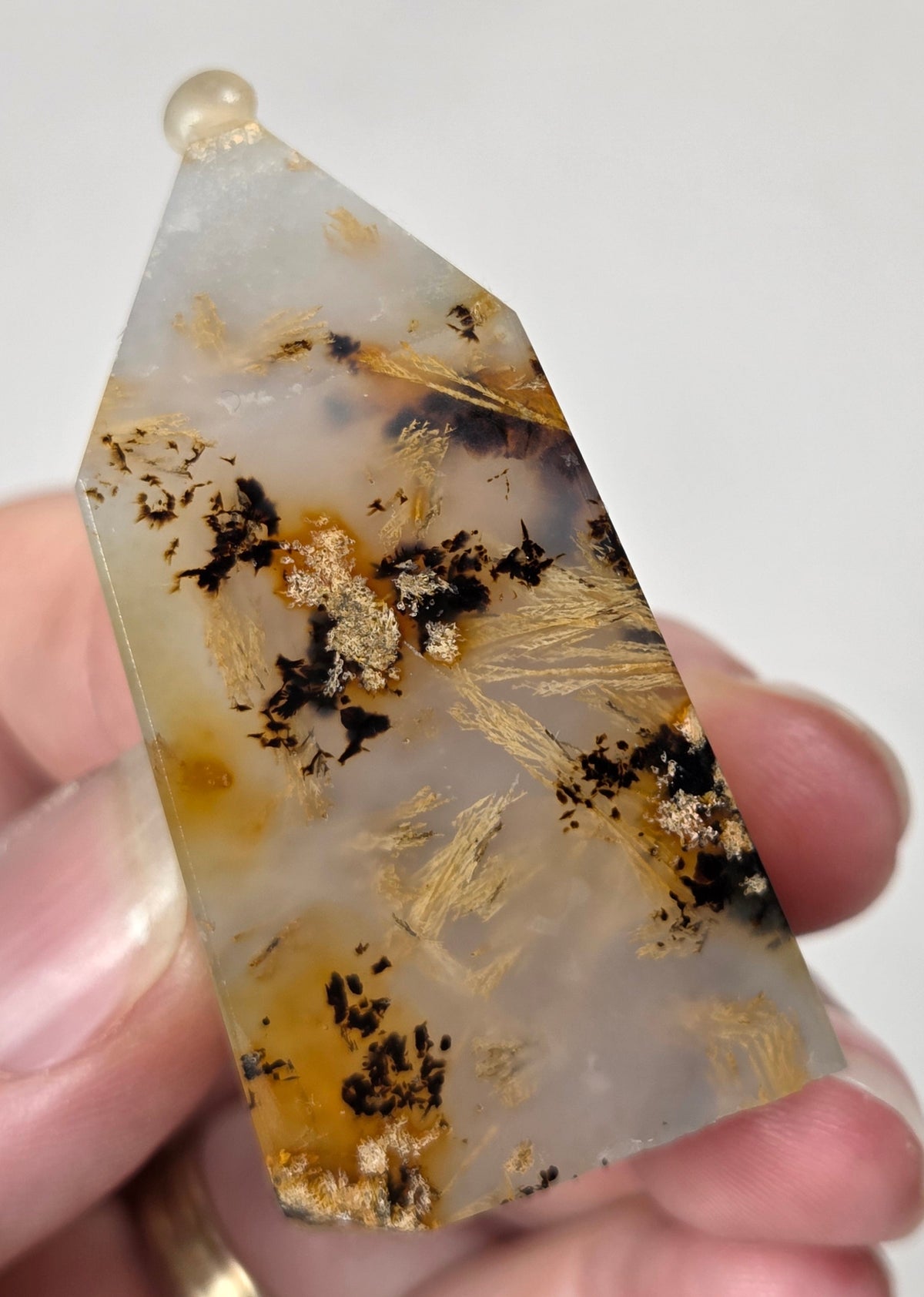 Close-up of a crystal point with inclusions against a white background