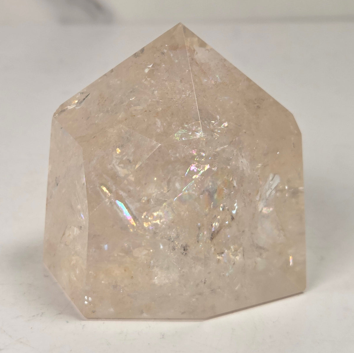 Clear Quartz polished tower with lots of rainbows on a white background