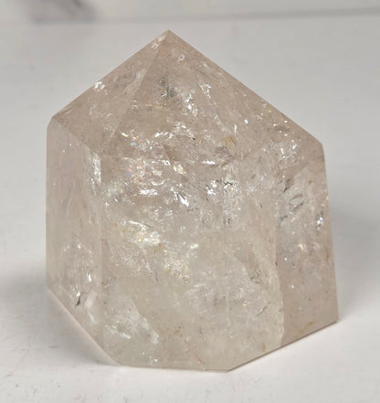 Clear Quartz polished tower with lots of rainbows on a white background