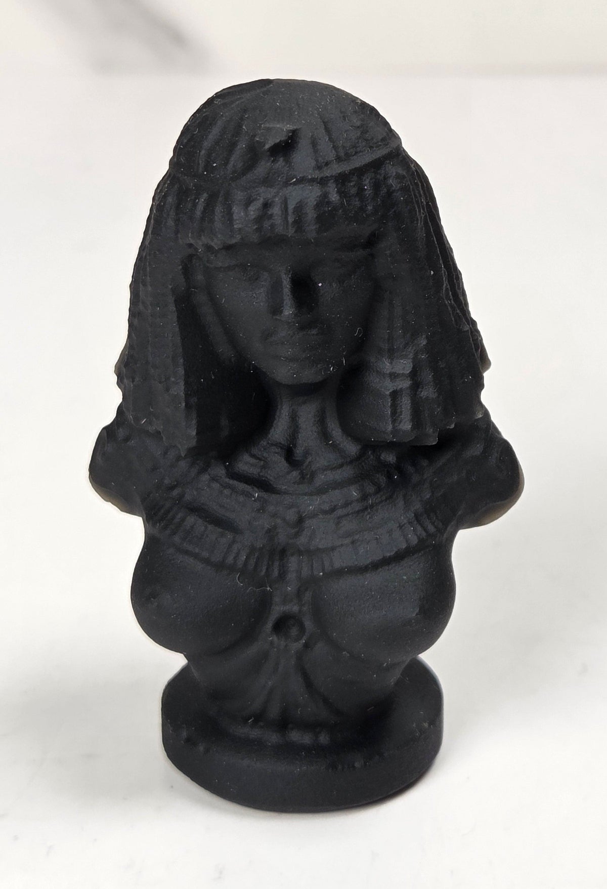 Obsidian carving of an egyptian queen against a marbled background