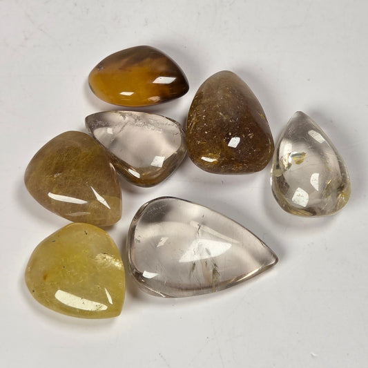 Collection of Clear quartz teardrrop shaped crystal with gold rutile inclusions held between fingers