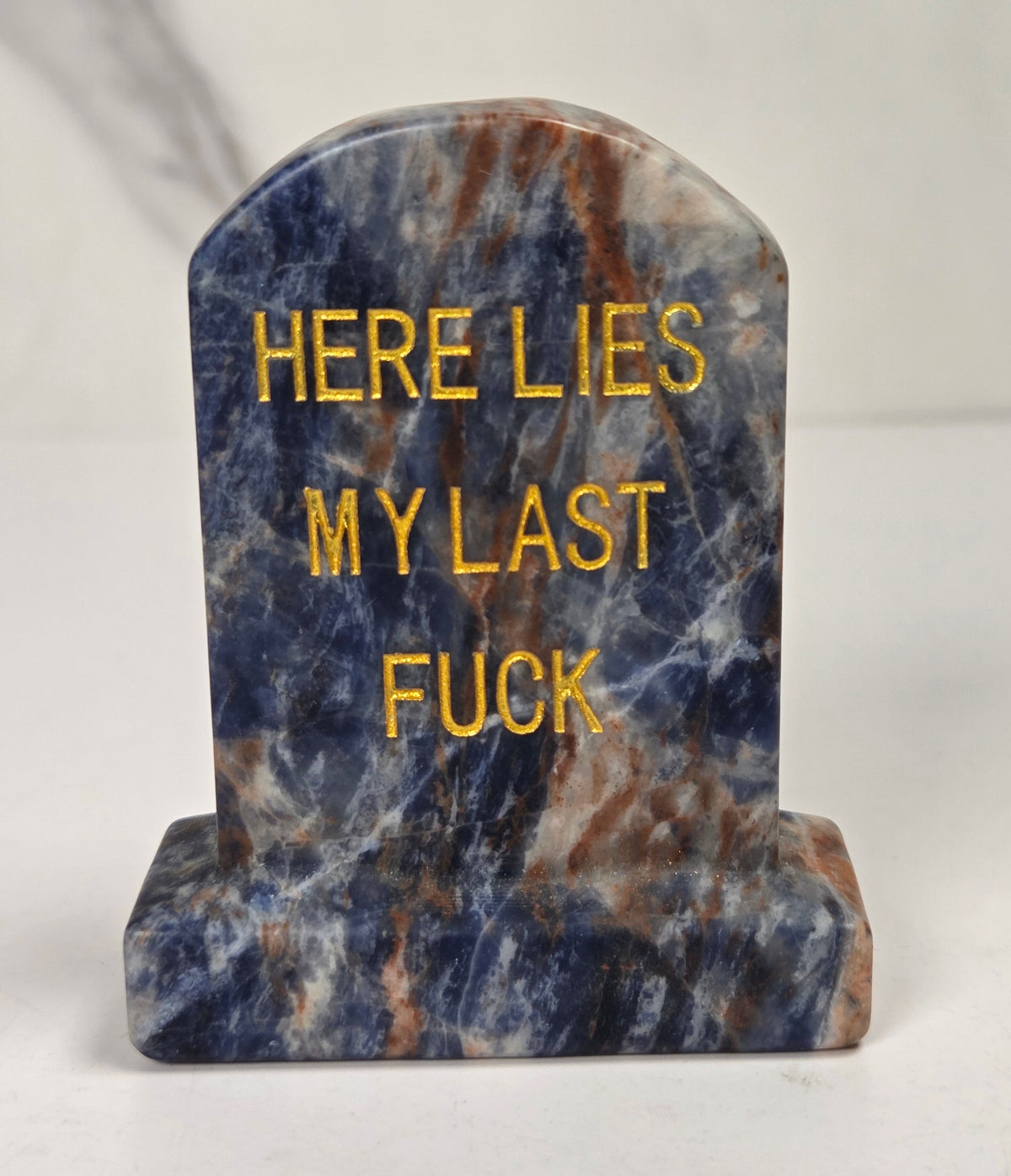 Blue and white crystal tombstone carving with gold lettering against a white background