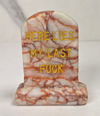 Red and white crystal tombstone carving with gold lettering against a white background