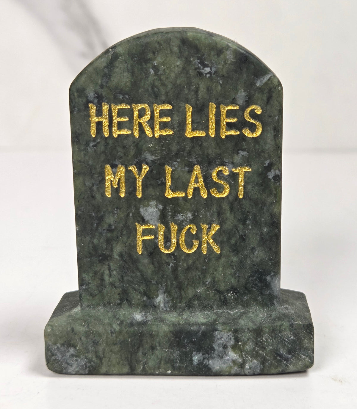 Green jade crystal tombstone carving with gold lettering against a white background