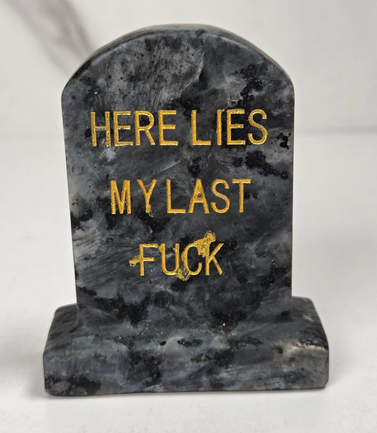 Black and grey crystal tombstone carving with gold lettering against a white background