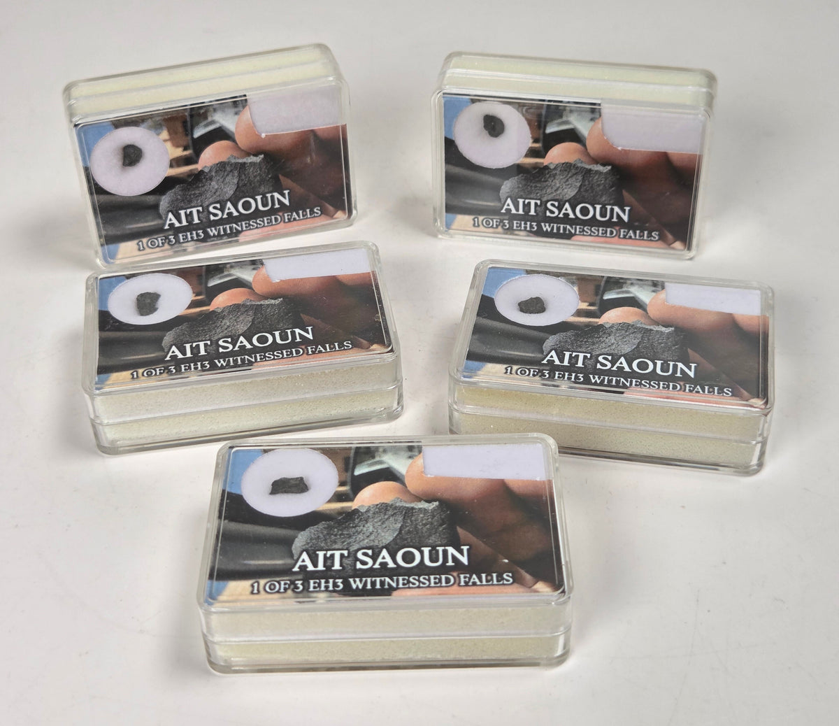 clear boxes with meteorite specimens against a white background