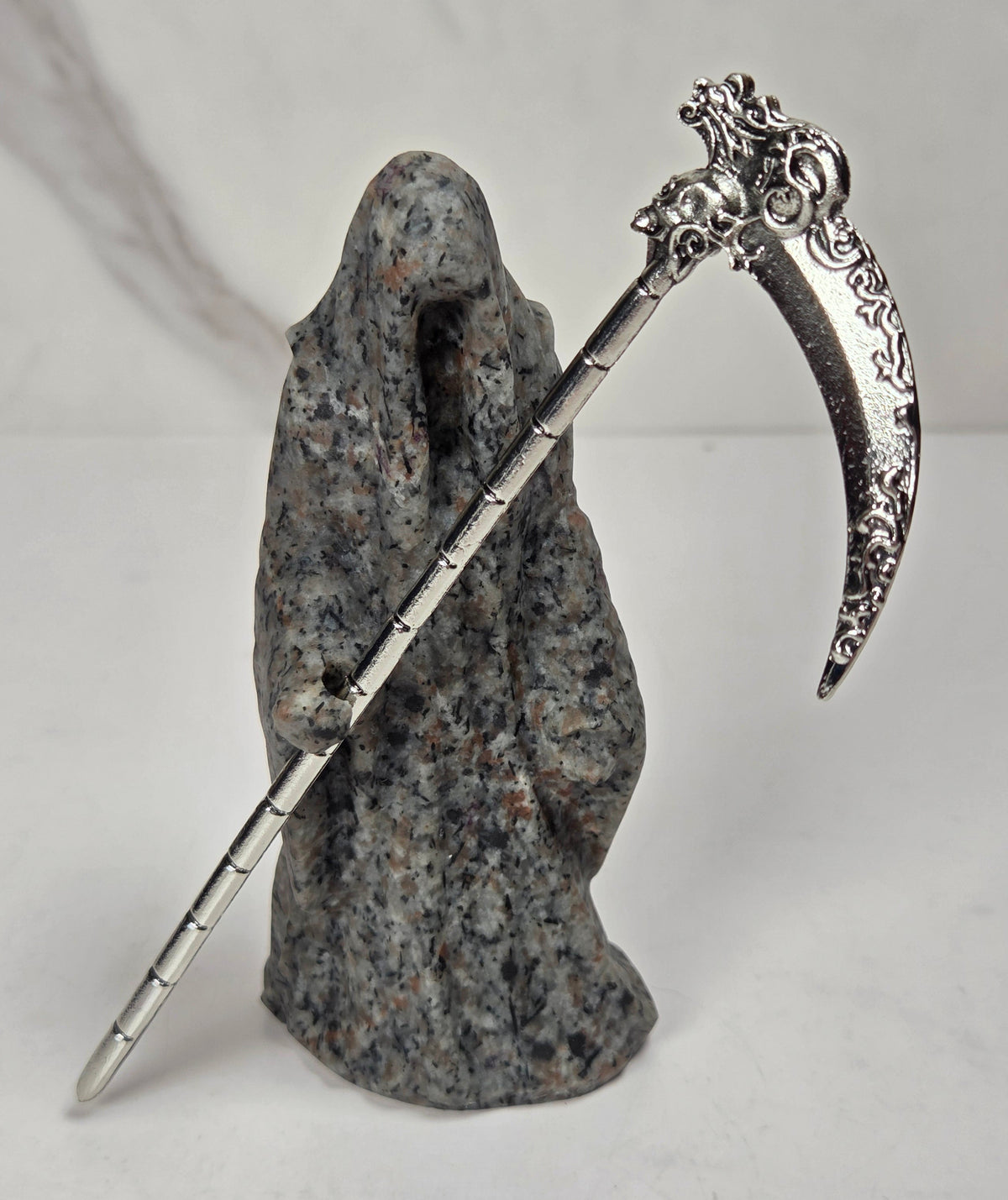 Reaper style crystal carving with black and grey coloring with a metal scythe against a marbled background