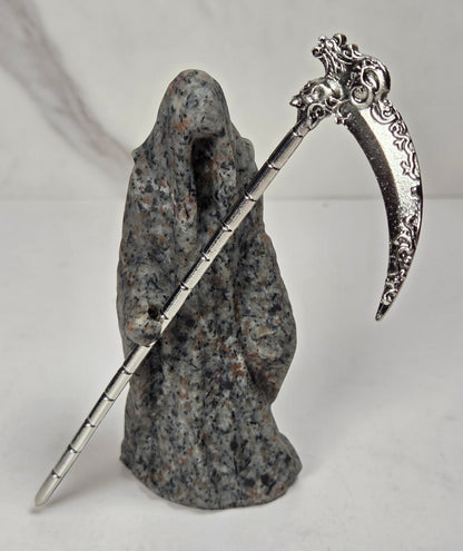 Reaper style crystal carving with black and grey coloring with a metal scythe against a marbled background