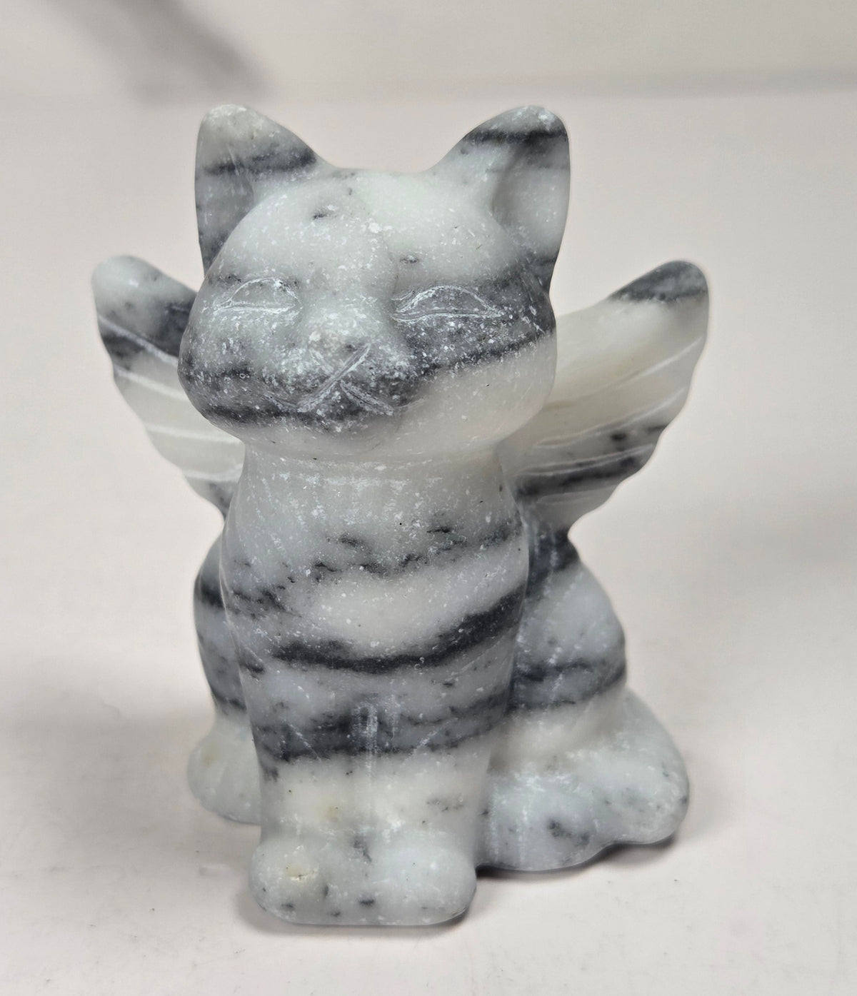 Crystal cat carving with wings made of white and black tai chi against a marbled background