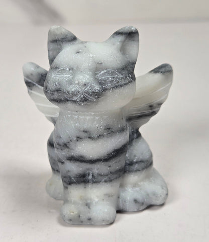Crystal cat carving with wings made of white and black tai chi against a marbled background