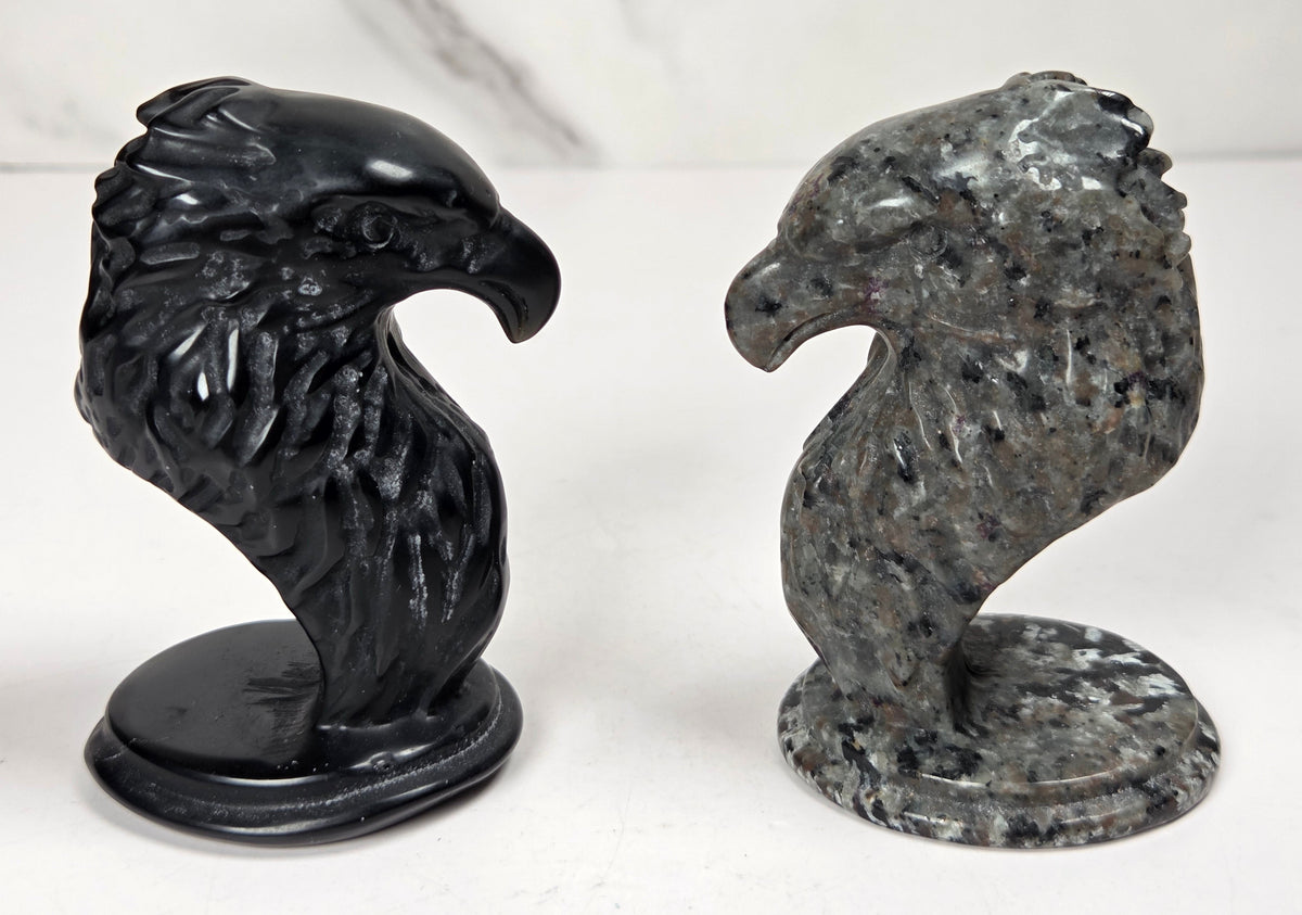 Crystal eagle head carvings in a variety of materials and colors against a marbled background