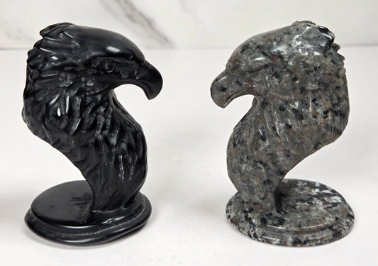 Crystal eagle head carvings in a variety of materials and colors against a marbled background