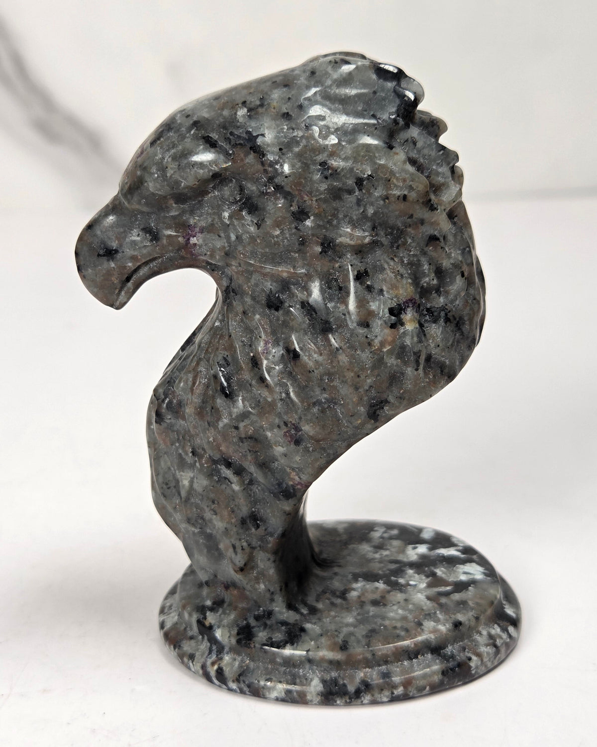 Crystal eagle head carving made of yooperlite against a marbled background