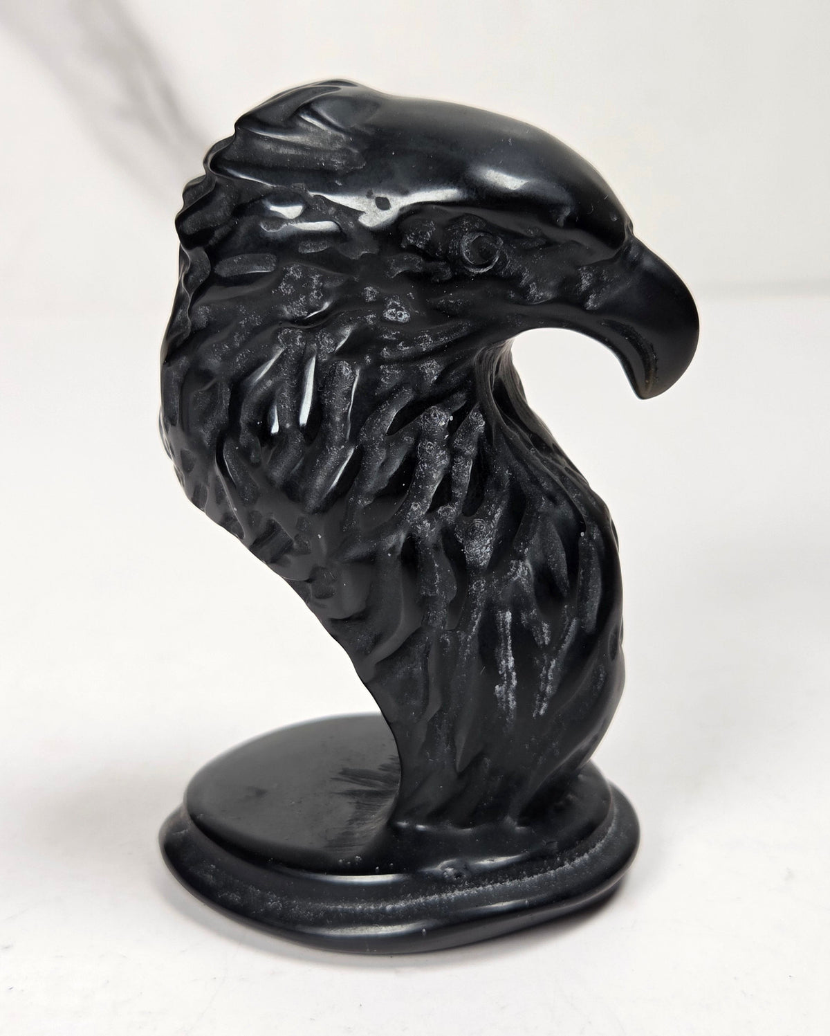 Crystal eagle head carving made of of obsidian against a marbled background