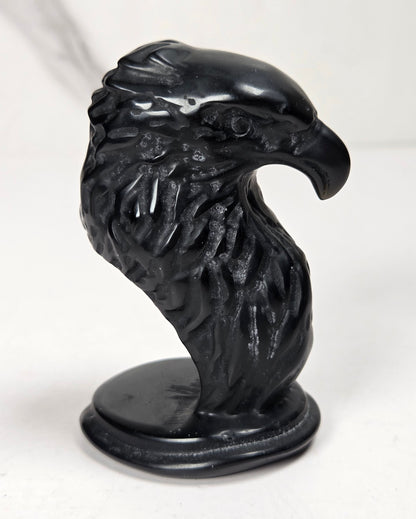 Crystal eagle head carving made of of obsidian against a marbled background