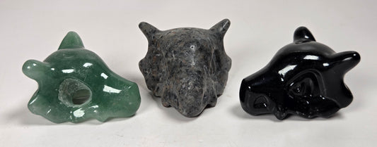 Stylized skull carvings made of different materials and colors against a white background
