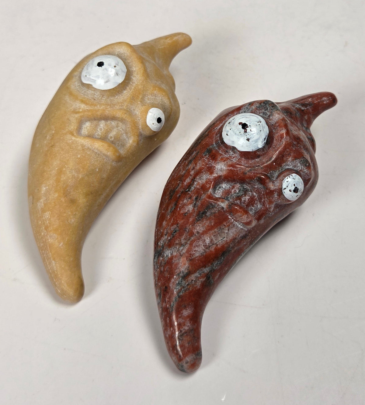 Crystal pepper carvings with two sized eyes against a white background