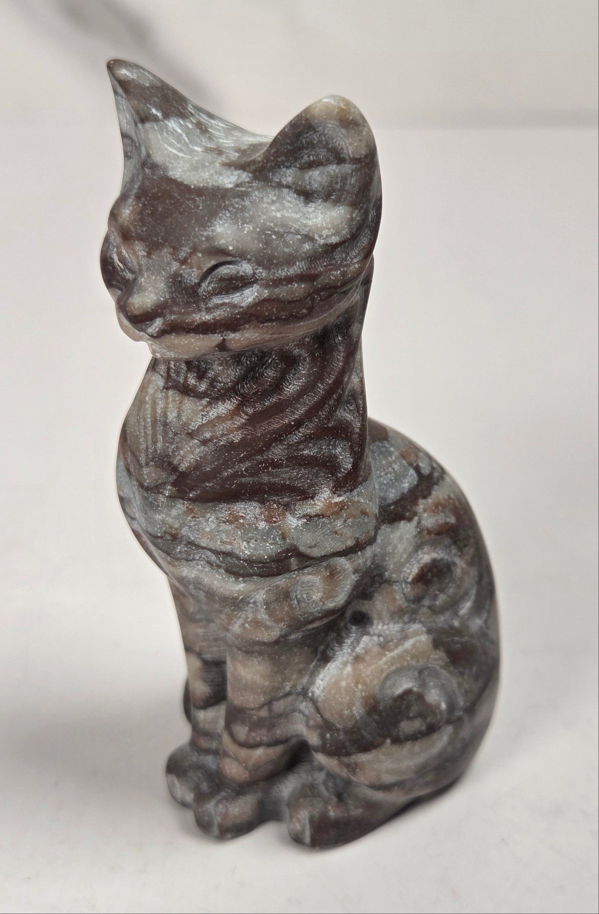 Brown banded crystal cat shaped carving with scroll work against a white background