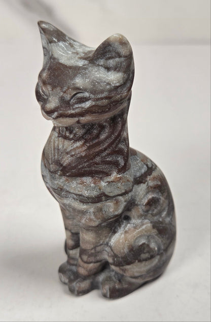 Brown banded crystal cat shaped carving with scroll work against a white background