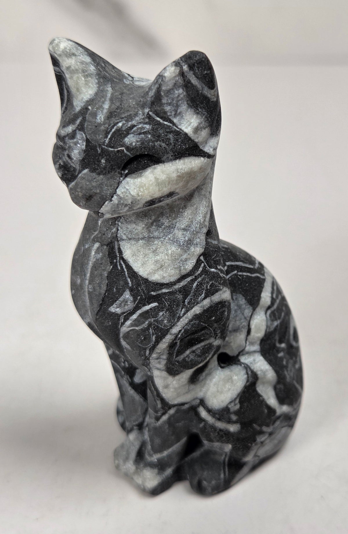 Black and white banded crystal cat shaped carving with scroll work against a white background