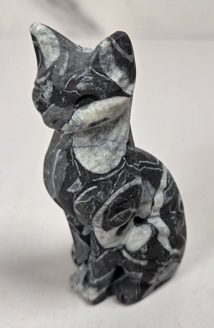 Black and white banded crystal cat shaped carving with scroll work against a white background