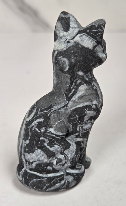 Black and white banded crystal cat shaped carving with scroll work against a white background