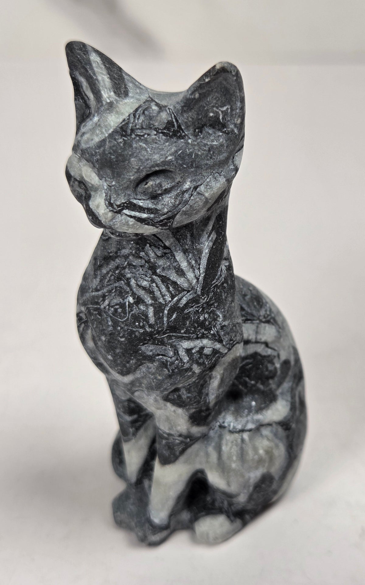 Black and white banded crystal cat shaped carving with scroll work against a white background