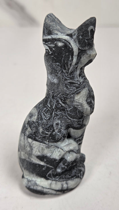 Black and white banded crystal cat shaped carving with scroll work against a white background