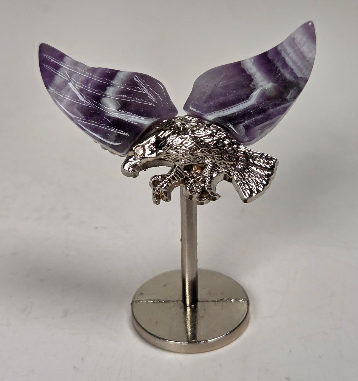 Purple and white crystal wings with a silver eagle on a silver stand against a white background