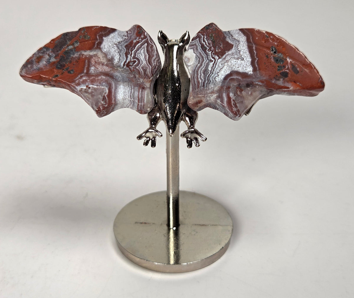 Red and white crystal bat wings on a silver stand against a white background