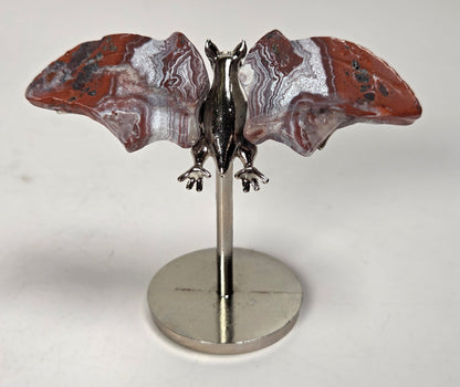 Red and white crystal bat wings on a silver stand against a white background