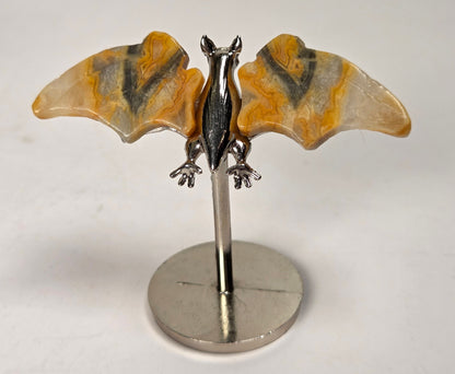 Yellow and black banded crystal bat wings on a silver stand against a white background