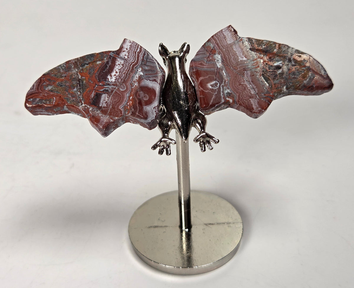 Red and white crystal bat wings on a silver stand against a white background