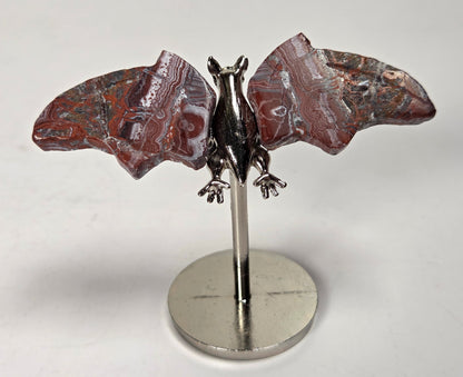 Red and white crystal bat wings on a silver stand against a white background