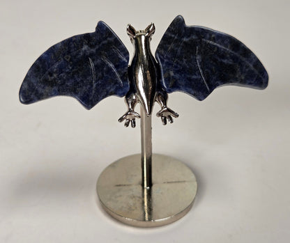 Dark blue crystal bat wings on a silver stand against a white background