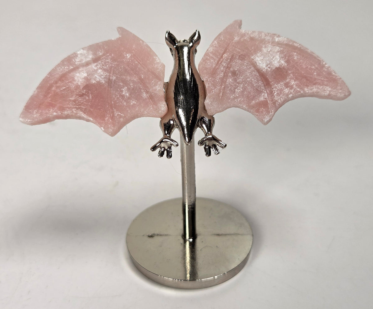 Pink crystal bat wings on a silver stand against a white background