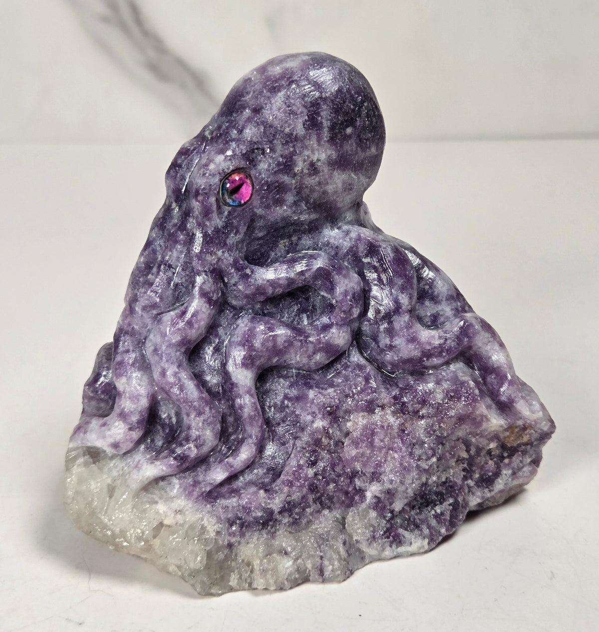 Purple crystal octopus carving with pink eyes against a marbled background