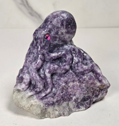 Purple crystal octopus carving with pink eyes against a marbled background