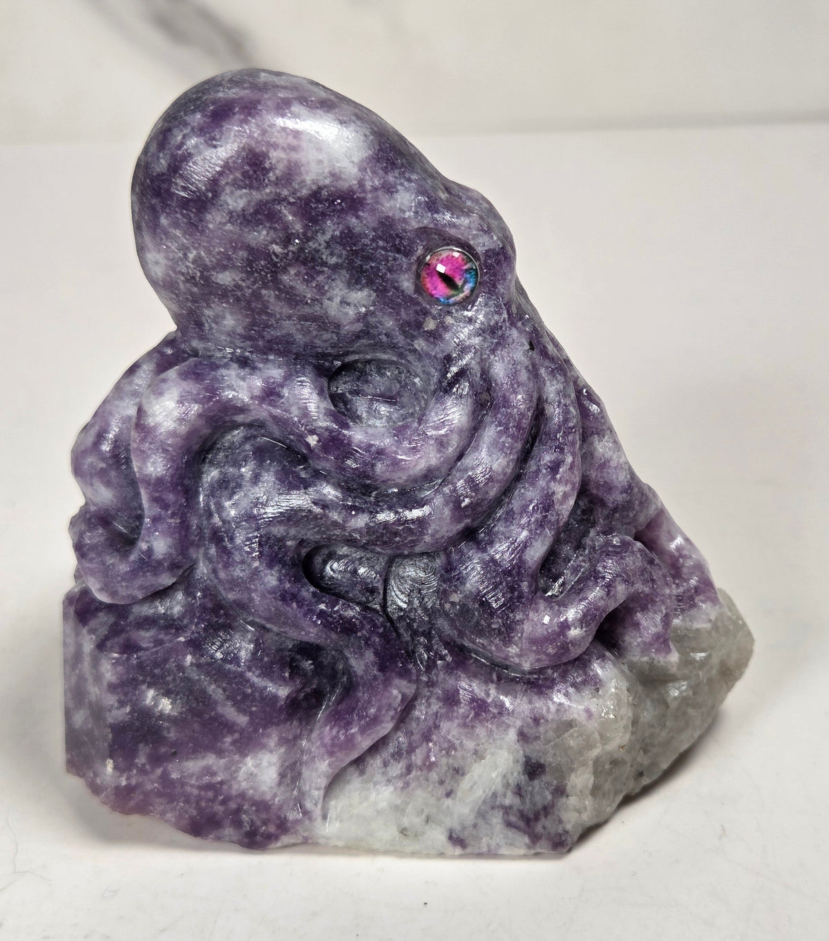 Purple crystal octopus carving with pink eyes against a marbled background
