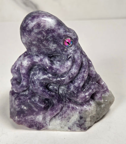 Purple crystal octopus carving with pink eyes against a marbled background