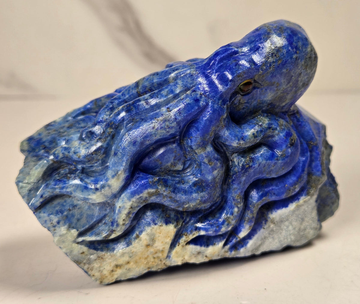 Blue crystal octopus carving with black  eyes against a marbled background