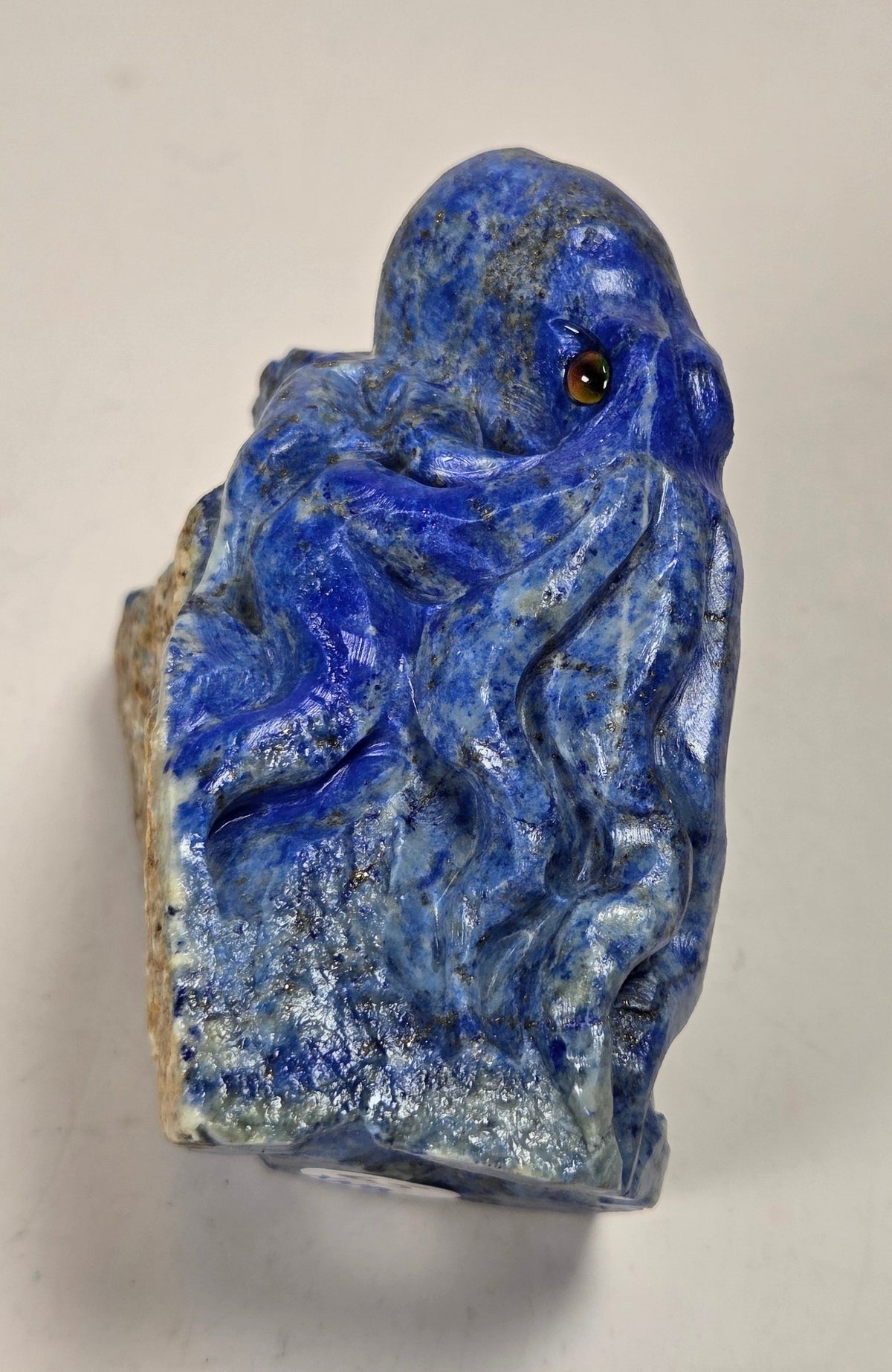 Blue crystal octopus carving with black  eyes against a marbled background