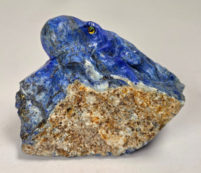 Blue crystal octopus carving with yellow  eyes against a marbled background