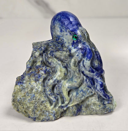 Blue crystal octopus carving with green  eyes against a marbled background