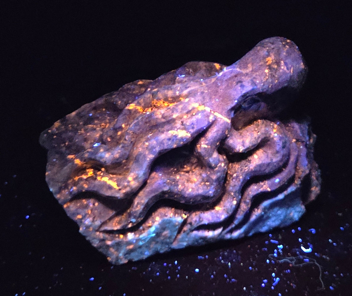 Blue crystal octopus carving with glowing orange under UV light against a marbled background