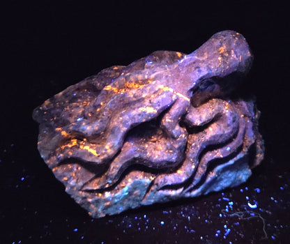 Blue crystal octopus carving with glowing orange under UV light against a marbled background