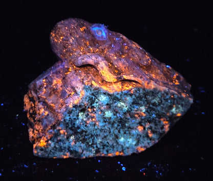 Blue crystal octopus carving with glowing orange under UV light against a marbled background