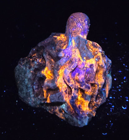 Blue crystal octopus carving with glowing orange under UV light against a marbled background